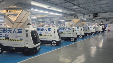 Rows of Neolix autonomous delivery vehicles parked in a facility in Beijing