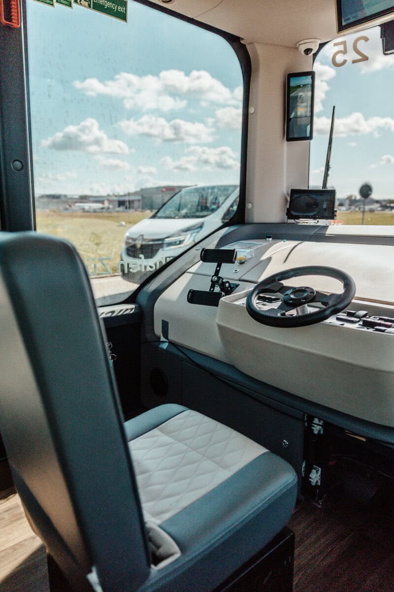 Empty safety driver seat and manual controls inside a Zurich Airport automated shuttle